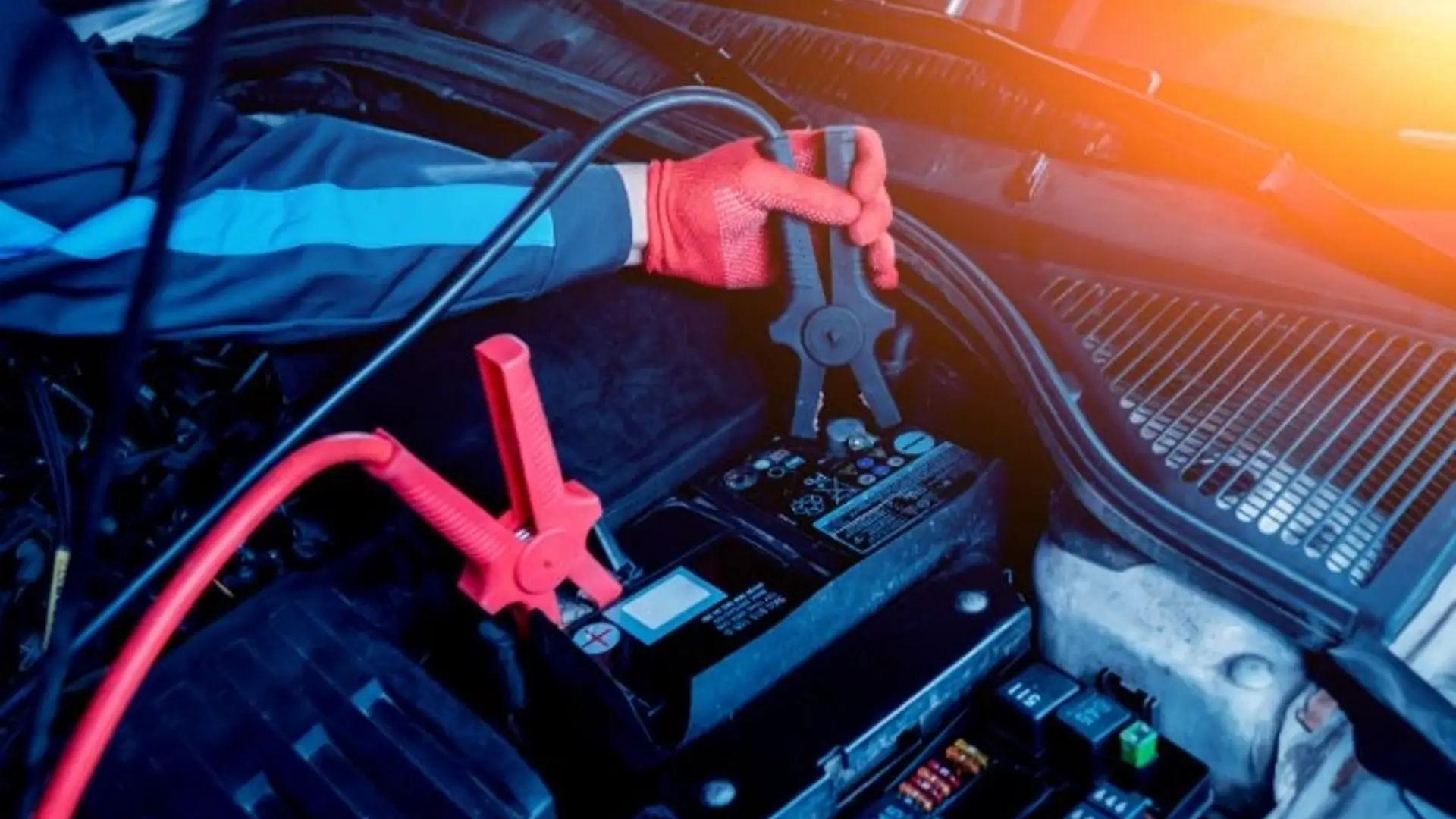 Autobatterie wird mit Starthilfekabeln im Motorraum aufgeladen