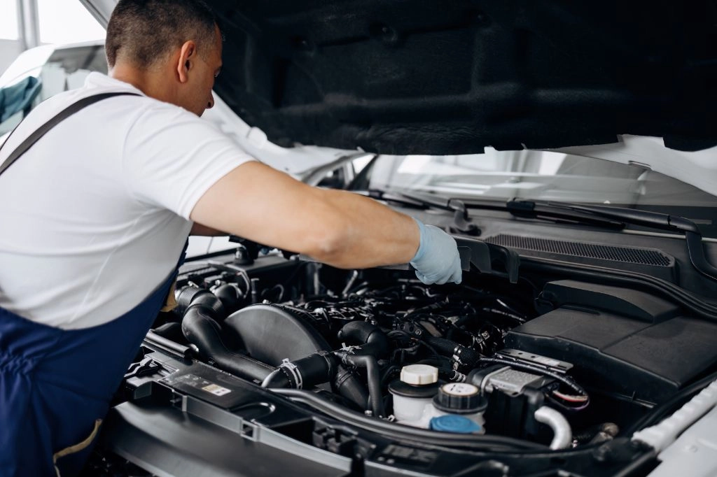 Automechaniker schraubt an Motor