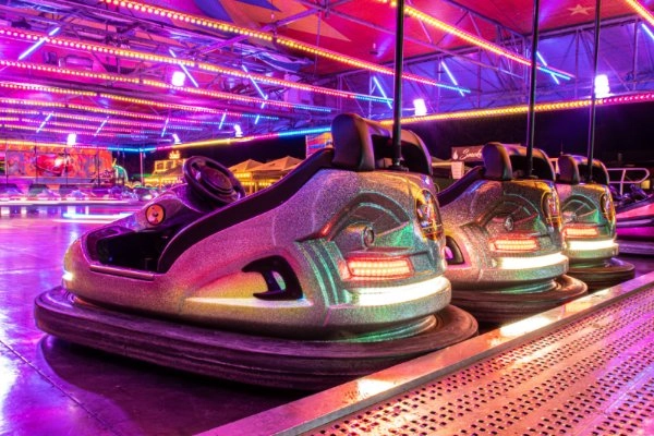 Autoscooter stehen unter buntem Neonlicht in einem Fahrgeschäft
