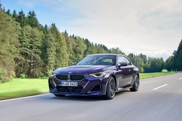 BMW M240i xDrive auf Straße mit Wald im Hintergrund