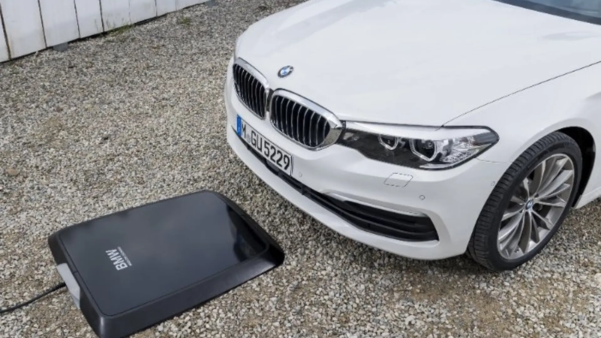Eine wireless-charging Platte liegt vor einem BMW auf dem Boden