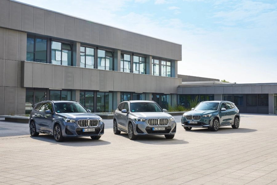 BMW X1 iX1 3 Generationen nebeneinander auf einem Gelände