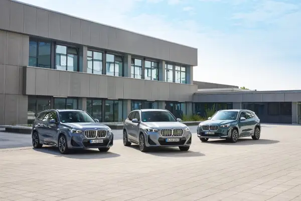 BMW X1 iX1 3 Generationen nebeneinander auf einem Gelände