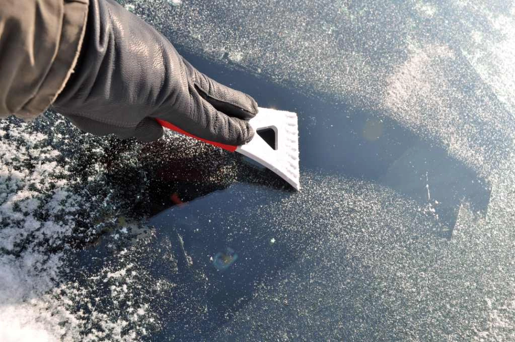 Vereiste Scheibe wird mit einem Eiskratzer frei gekratzt