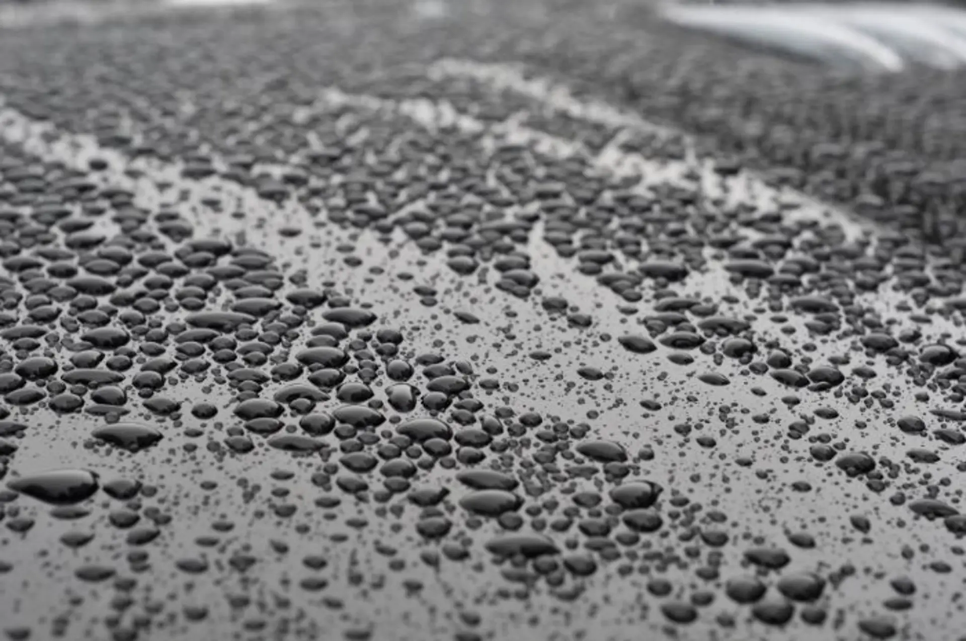 Wassertropfen perlen durch Lotus-Effekt von einer lackierten Fahrzeugoberfläche ab