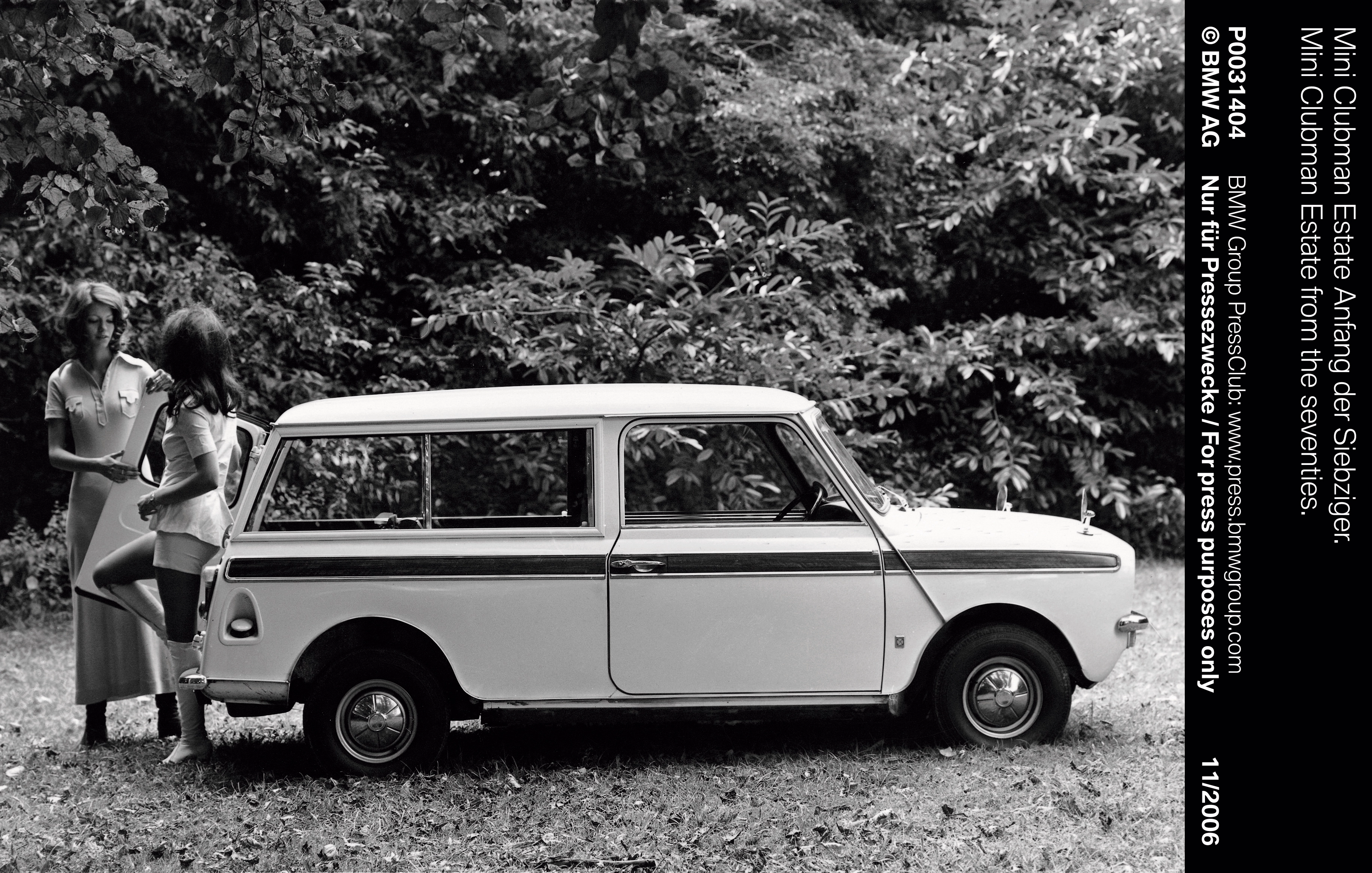 Ein Schwarzweißbild zeigt zwei Frauen stehen an einem alten Mini Clubman von 1969