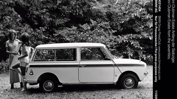 Ein Schwarzweißbild zeigt zwei Frauen stehen an einem alten Mini Clubman von 1969