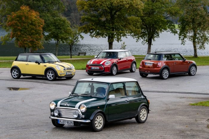 Verschiedene Mini Cooper Modelle aus verschiedenen Generationen stehen verteilt auf einem Parkplatz