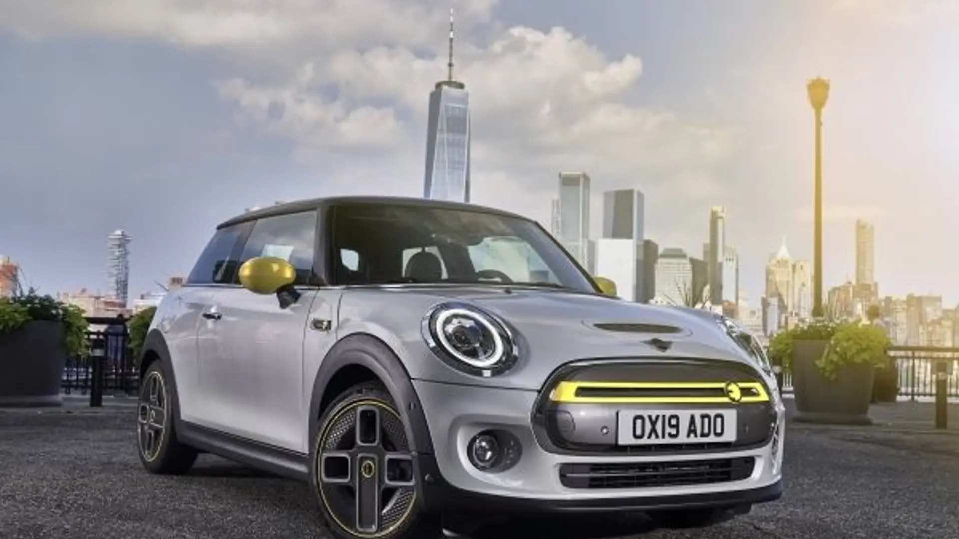 Grauer MINI Countryman Cooper SE Plug-in Hybrid steht vor urbaner Skyline mit Hochhäusern im Hintergrund