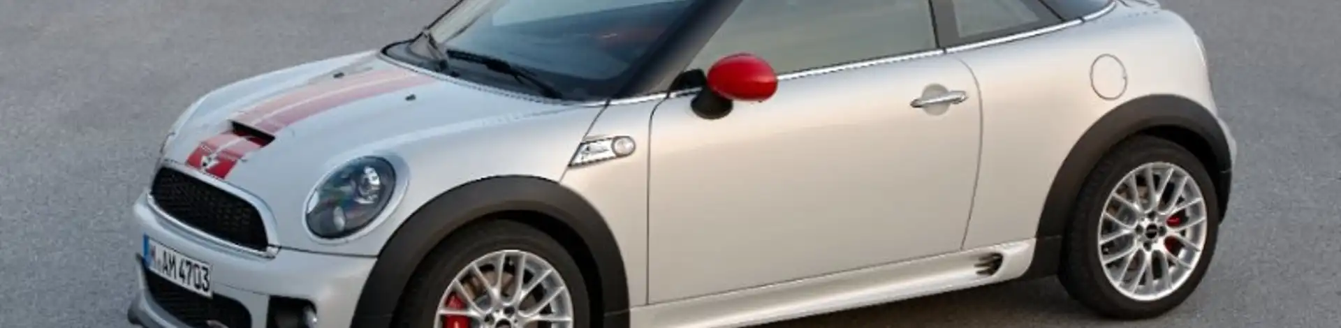 Weißer MINI Coupé Baujahr 2011 mit rotem Dach steht auf Asphaltfläche