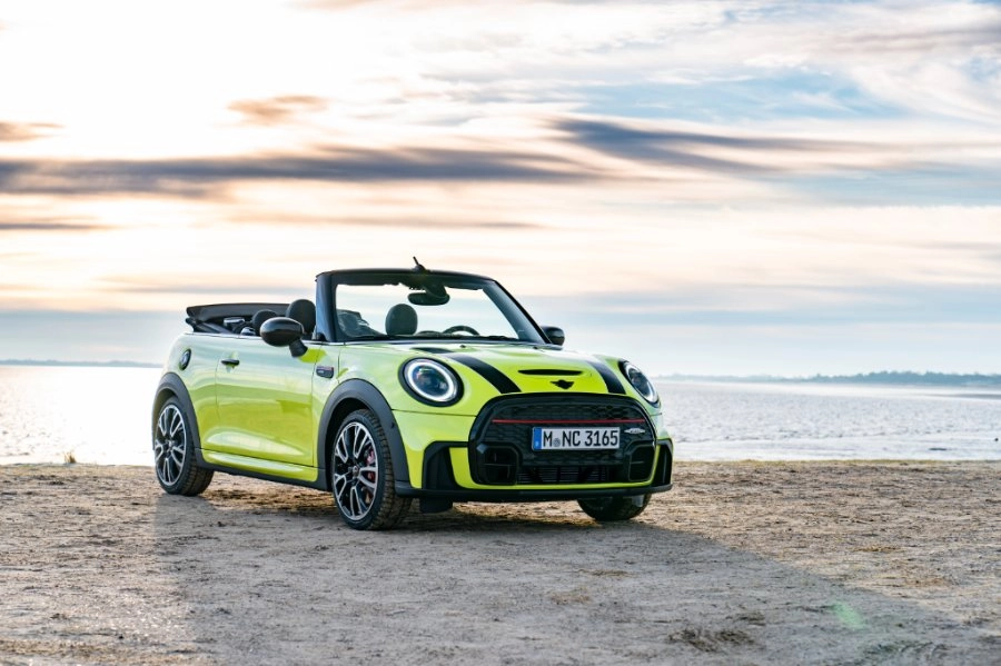 Neongelber Mini Cooper steht am Strand bei Sonnenuntergang
