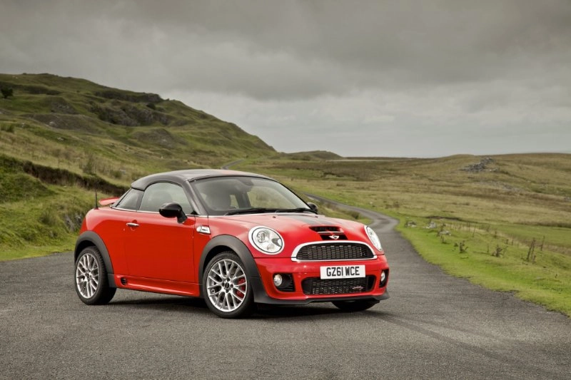 Roter MINI John Cooper Works Coupé steht schräg auf einer Landstraße in hügeliger Landschaft