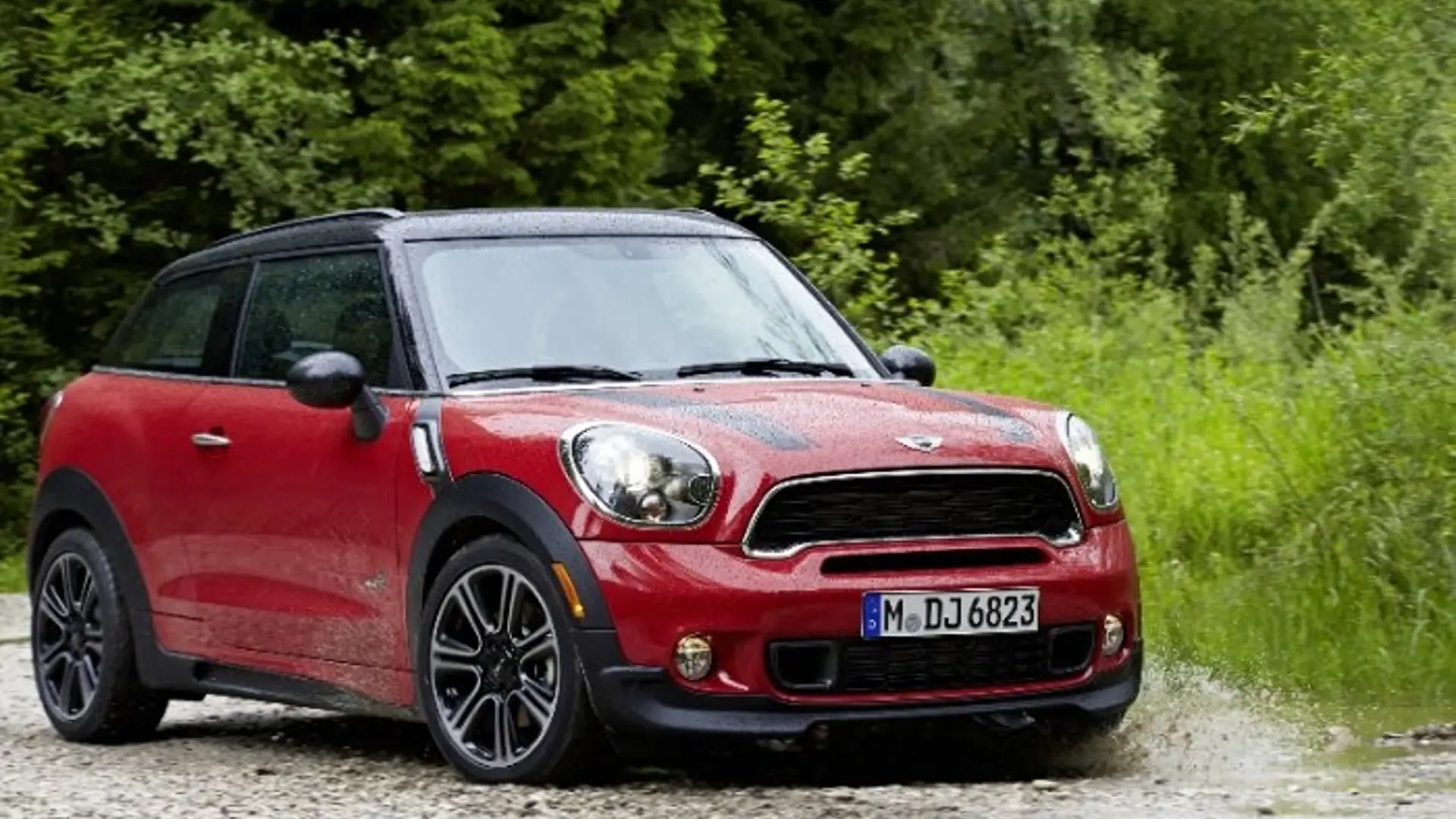 Roter MINI Paceman Cooper S All4 steht auf Schotterweg vor grüner Vegetation