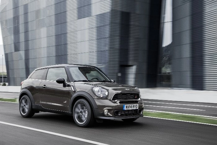 Grauer MINI Paceman Facelift fährt an modernen Gebäuden vorbei