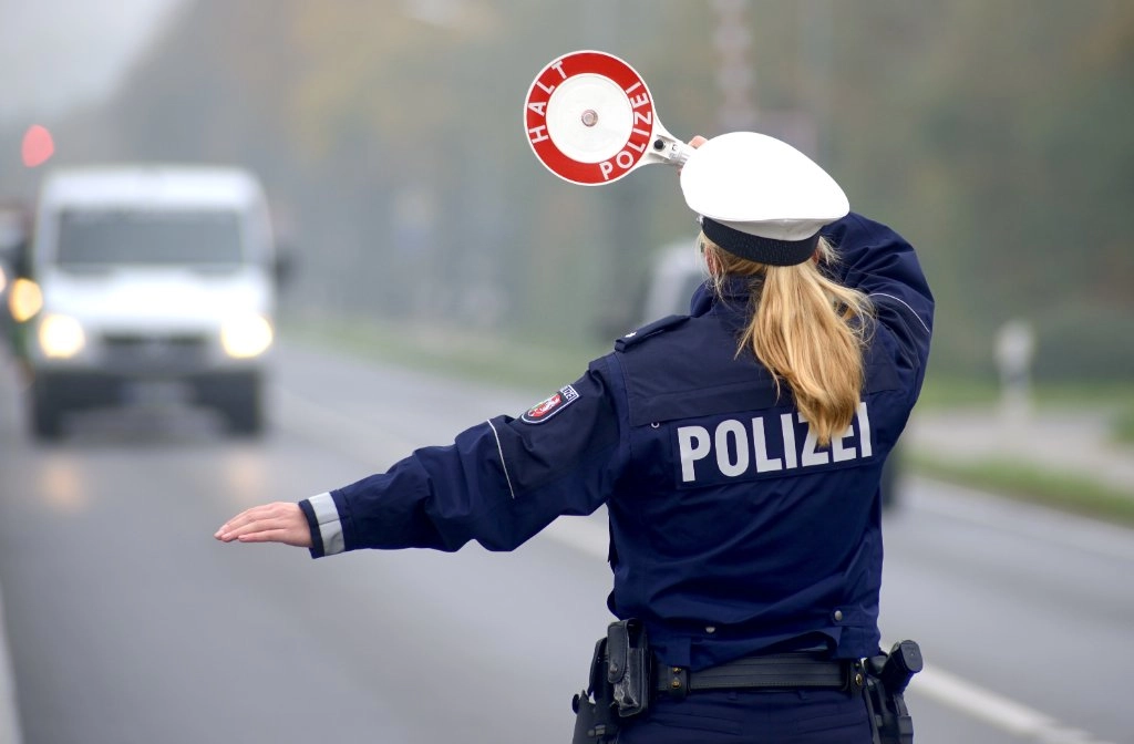 Polizistin mit Stopkelle winkt kleinen Laster in der Ferne heraus