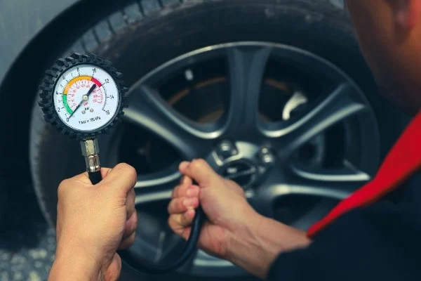 Person, die den Luftdruck eines Autoreifens überprüft