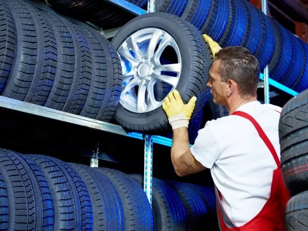 Autowerkstatt-Mitarbeiter lagert Reifen im Regal ein