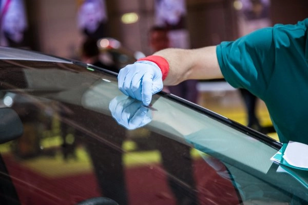 Person führt Smart-Repair an einer Autoscheibe durch und bearbeitet einen Steinschlag
