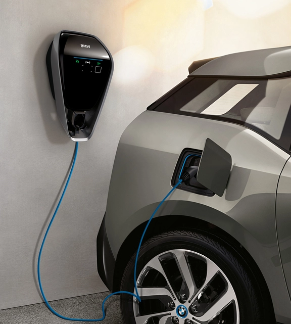 BMW i3 ist an einer Wallbox-Ladestation angeschlossen, das Ladekabel führt von der Wand zum geöffneten Ladeanschluss am Fahrzeug